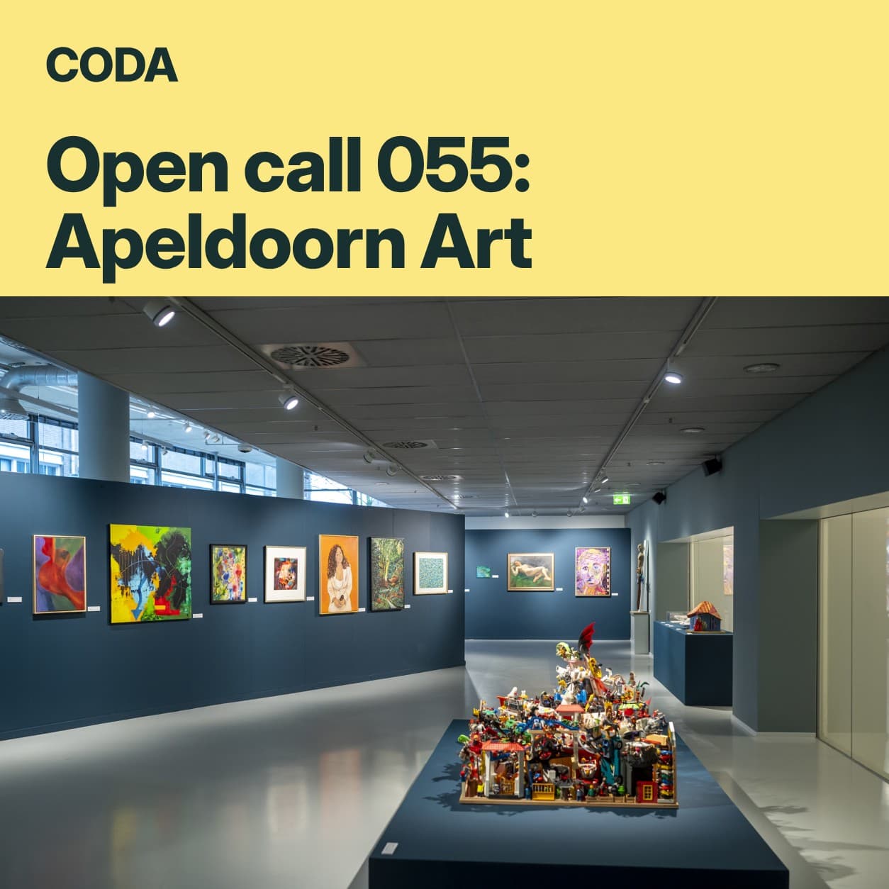 Open call 055: Apeldoorn Art in CODA: een gele balk met de titel boven een expositiezaal met donkerblauwe wanden en schilderijen.