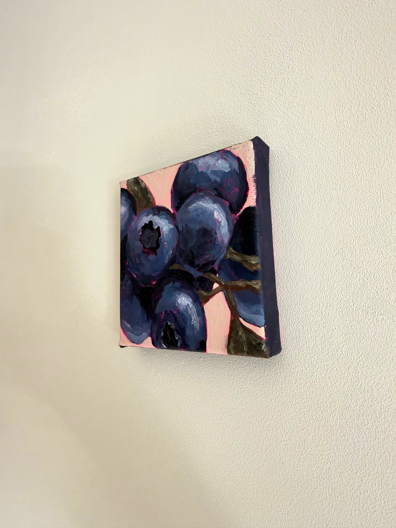 Het bessenschilderij schuin van opzij aan een lichte muur.