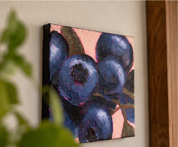 Close-up van Blueberries schuin aan de muur: de dik geschilderde blauwe en violette bessen, olijfgroene steeltjes en roze randen.