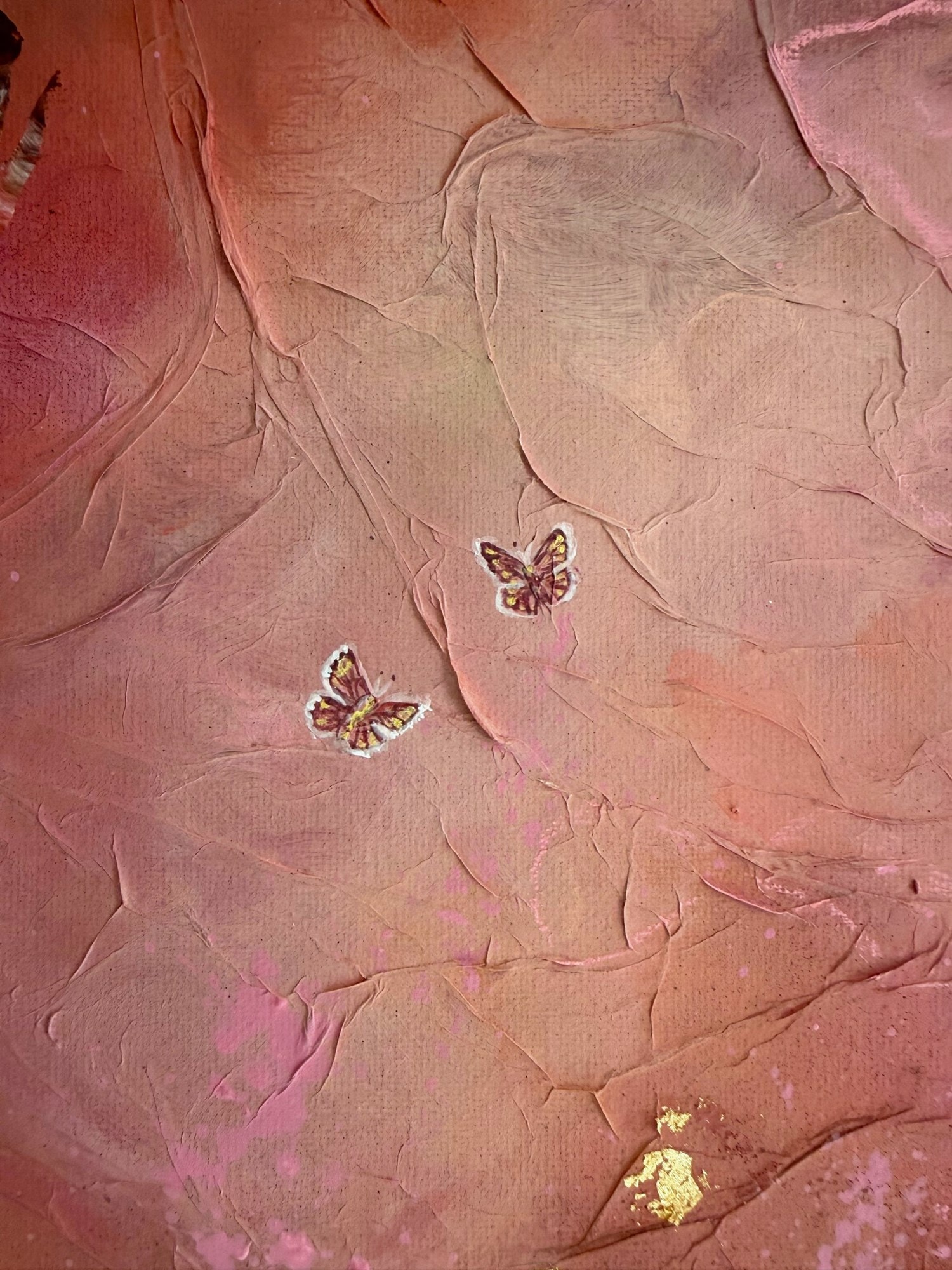 Detail van de twee kleine geschilderde vlinders op het gekreukte roze oppervlak.