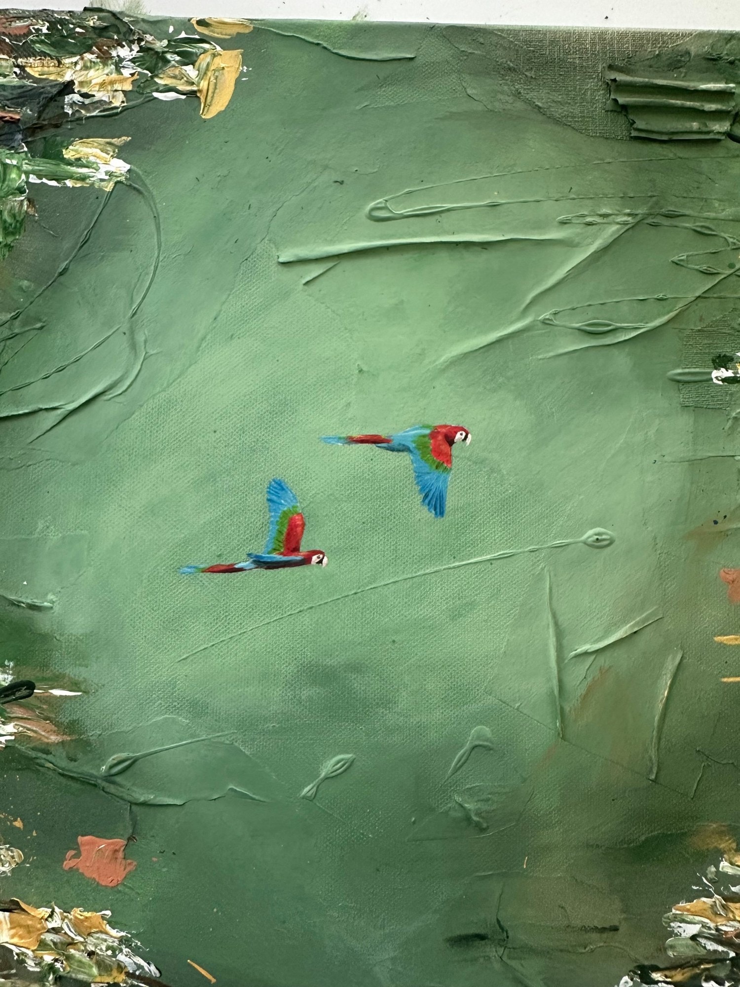 Detail van de twee kleine papegaaien in vlucht boven het groene reliëfoppervlak.